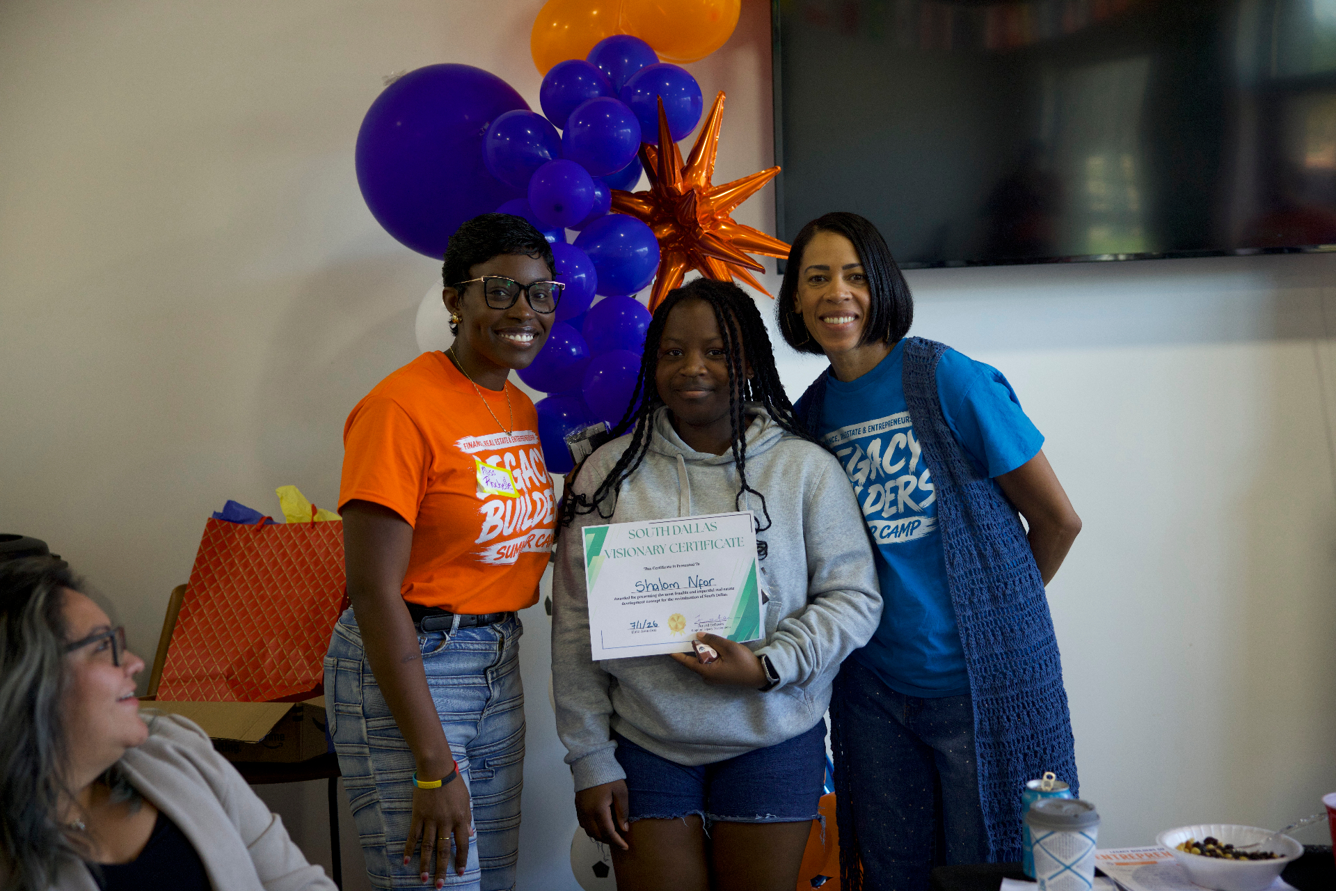 Two mentors celebrating an Academy student holding her South Dallas Visionary certificate